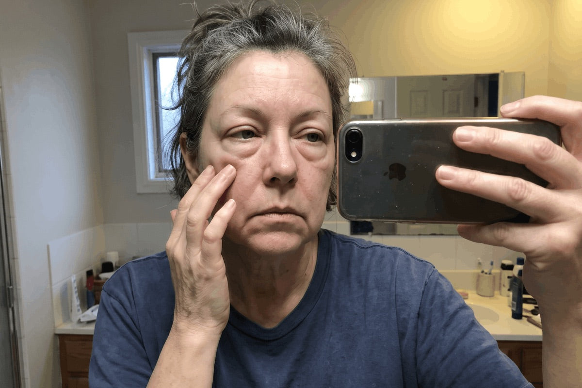 Woman checking her puffy under-eyes in the bathroom mirror